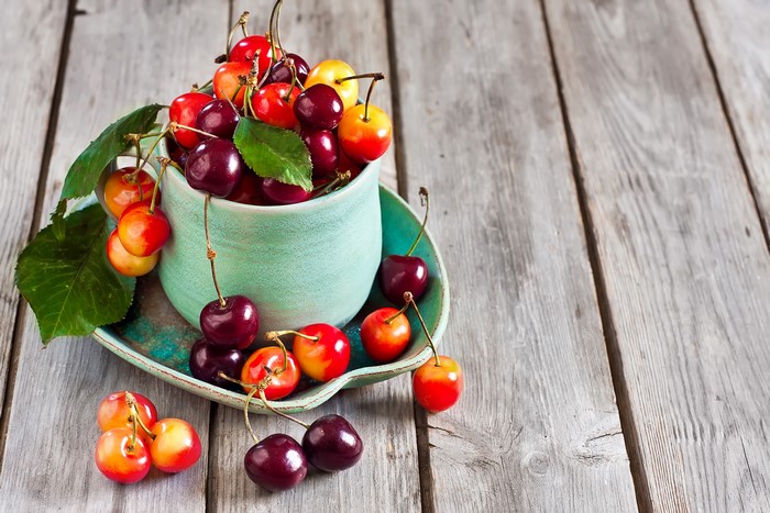 Cherries in a cup on a wooden table