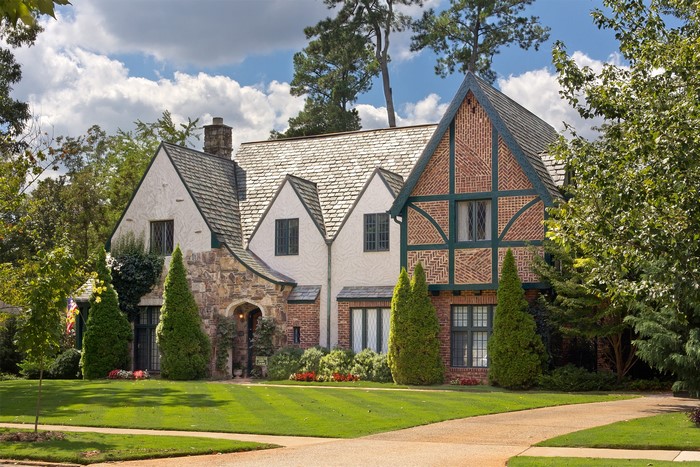 Tudor-style house with manicured lawn and trees
