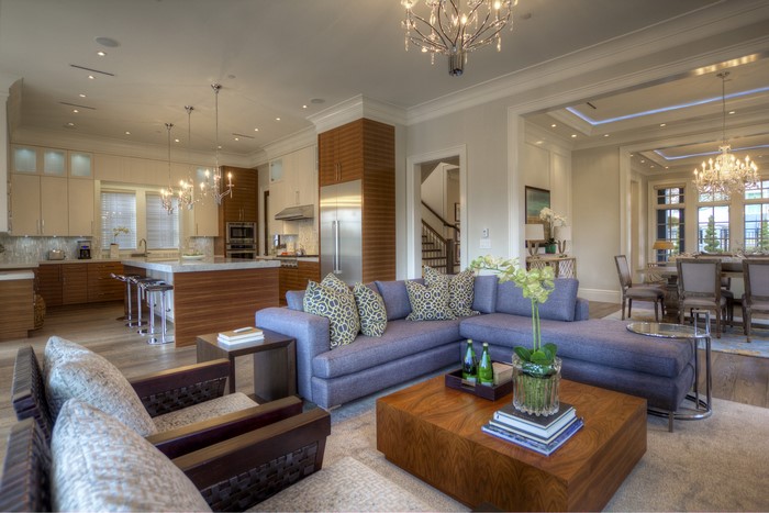 Modern living room and kitchen with purple sofa and chandelier
