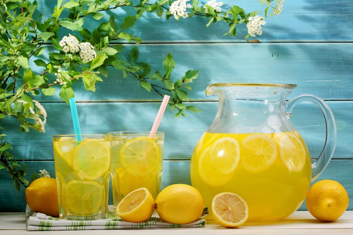Lemonade in pitcher and glasses with lemons