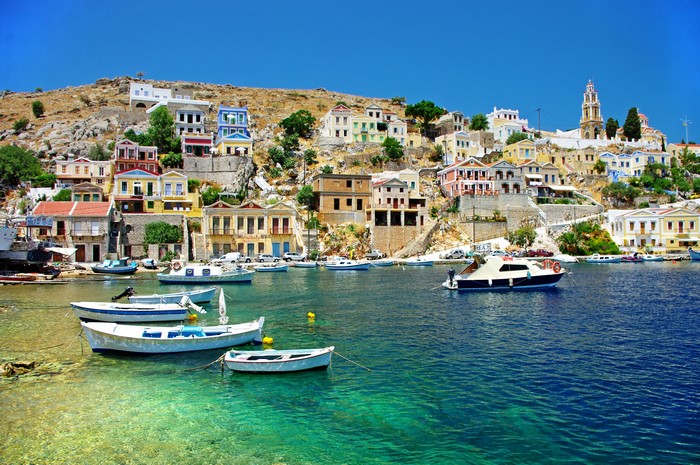 Colorful houses on a hill overlooking a harbor with boats in Greece