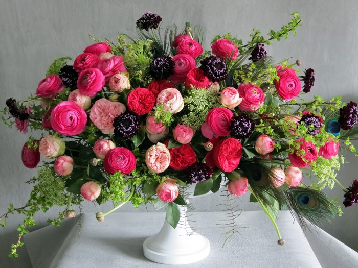 Pink and red ranunculus and rose bouquet with peacock feathers