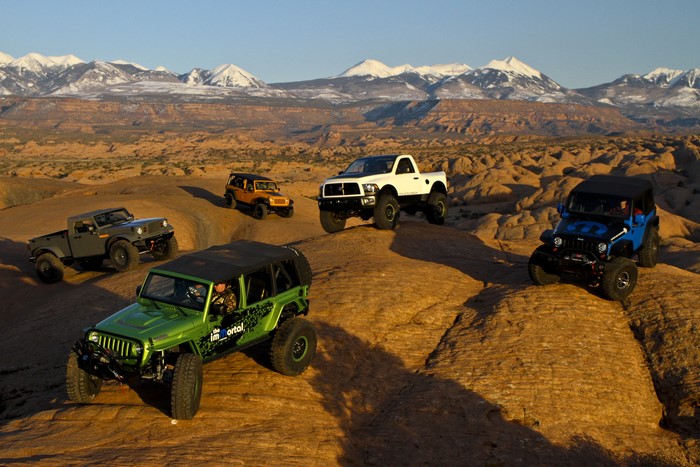 Jeeps on rocky terrain with snow-capped mountains