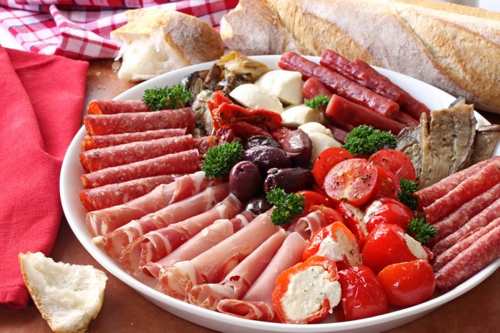 Charcuterie board with meats, cheese, tomatoes, and bread