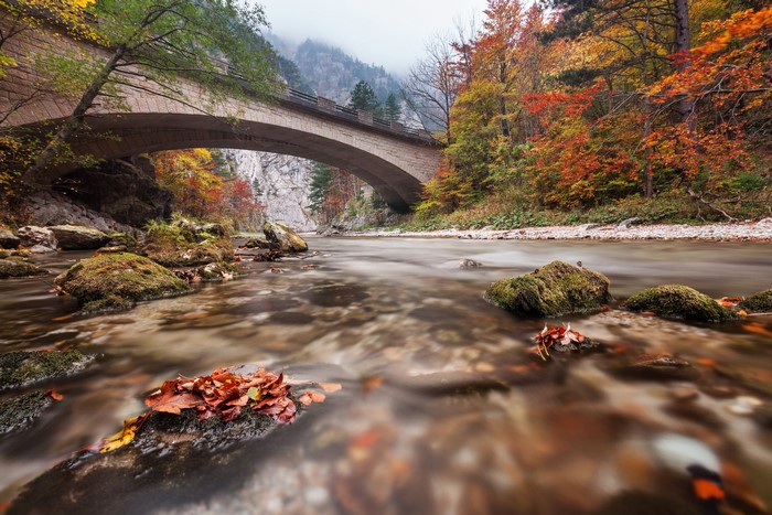 Stone bridge over a river in autumn forest, Austria