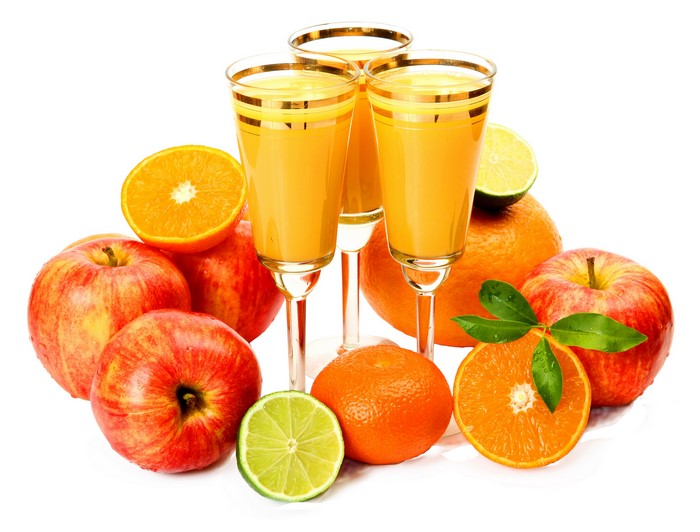 Juice in glasses with apples, oranges, and limes