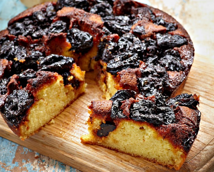 Plum cake with prunes on a wooden board
