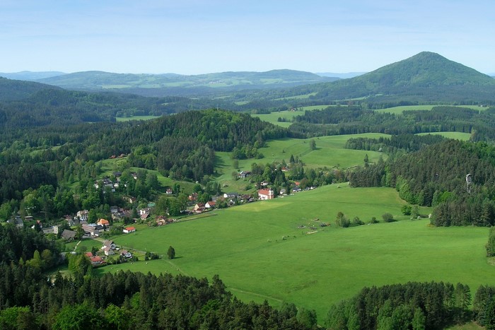 View of a village in a valley with rolling hills and forests