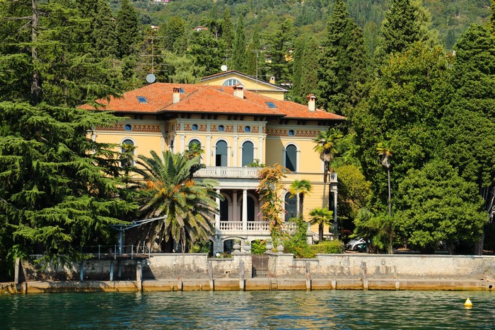Yellow mansion on a lake with palm trees and cypress trees
