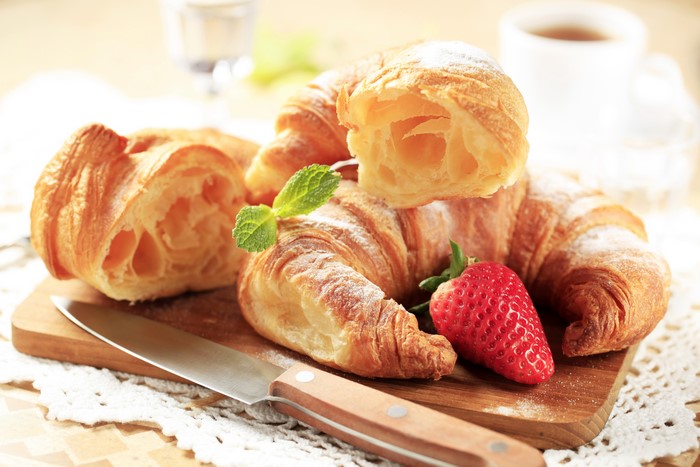 Croissants with strawberry and mint on a wooden board