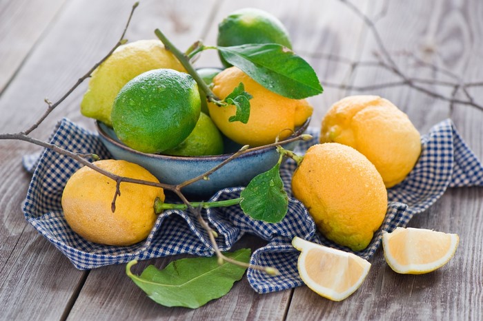 Lemons and limes in a bowl on a checkered cloth