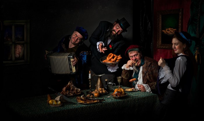People feasting and playing music in a dimly lit room
