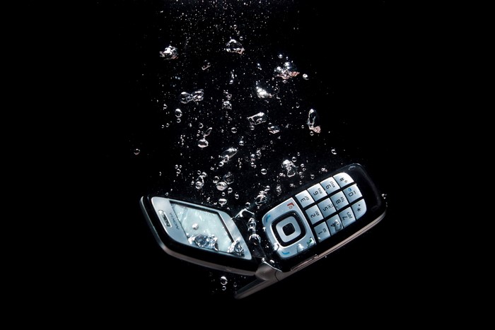 Flip phone sinking in water with bubbles