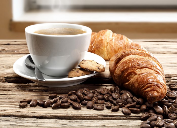 Coffee cup with croissants and coffee beans