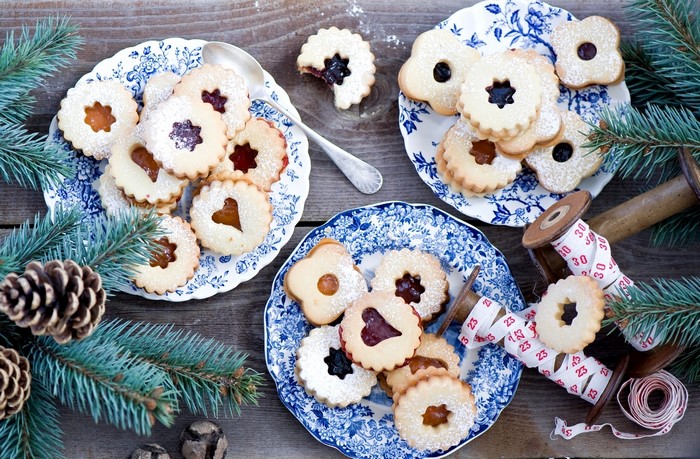 Christmas Linzer cookies on blue and white plates with pine branches
