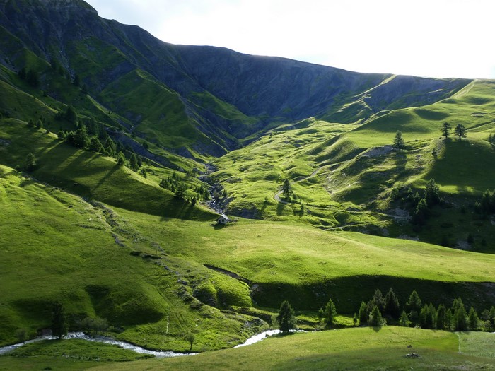 Green mountain valley with a stream and a small house