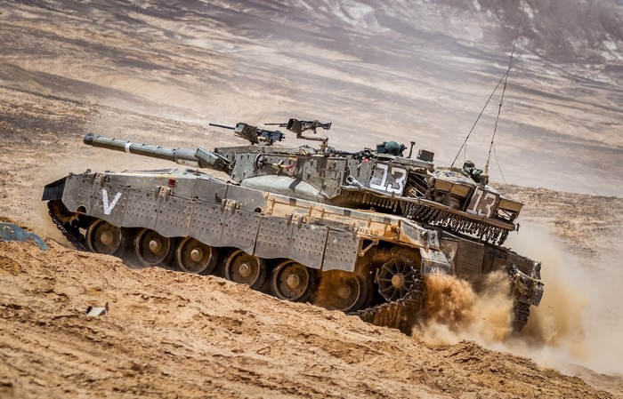 Merkava tank moving through a desert landscape