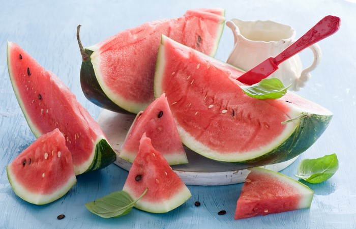 Slices of watermelon with basil leaves and a knife