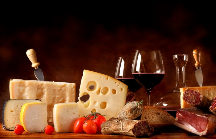 Still-life of cheese, meats, wine, and tomatoes
