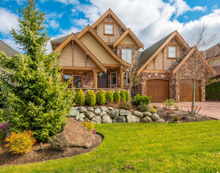 Luxury house with stone and wood exterior and manicured lawn