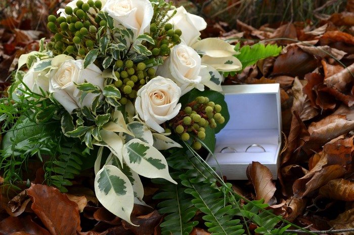 White roses bouquet and wedding rings in a box