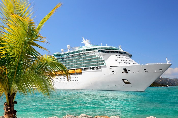 Cruise liner sailing in turquoise water near palm tree