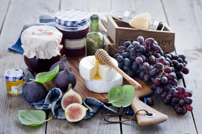 Still life with grapes, figs, cheese, jam, and honey