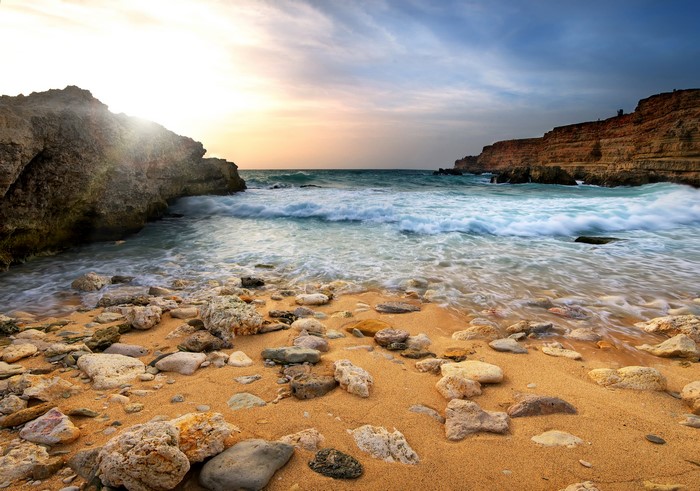 Rocky beach with waves crashing on shore at sunset