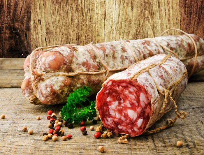 Sausage with spices on a wooden background
