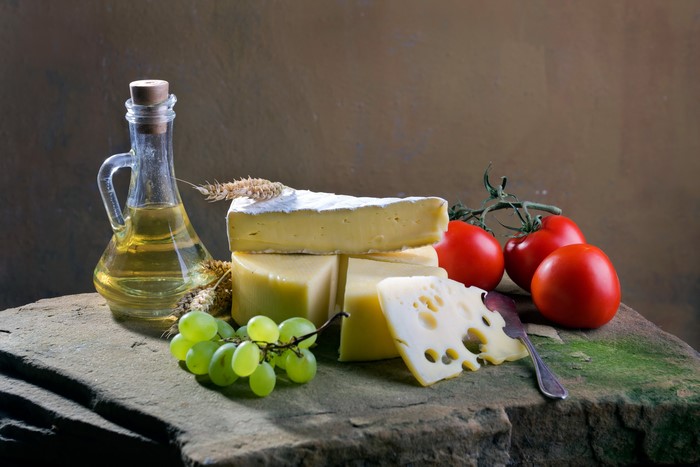 Still life with cheese, tomatoes, grapes, and oil bottle