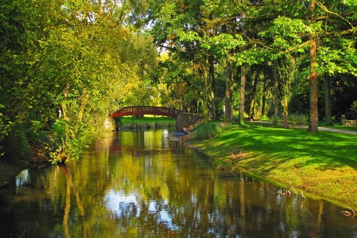 Park with a river and a red bridge in Sochaczew, Poland