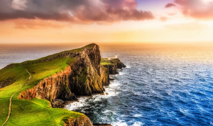 Lighthouse on a cliff overlooking the sea at sunset in Scotland