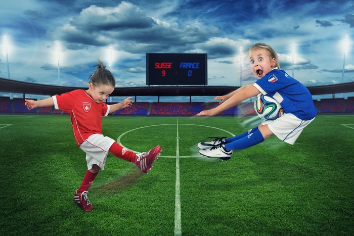 Two young girls playing soccer in a stadium