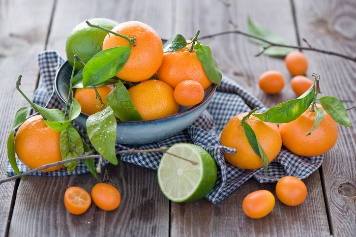 Citrus fruits and limes in a bowl on a wooden table