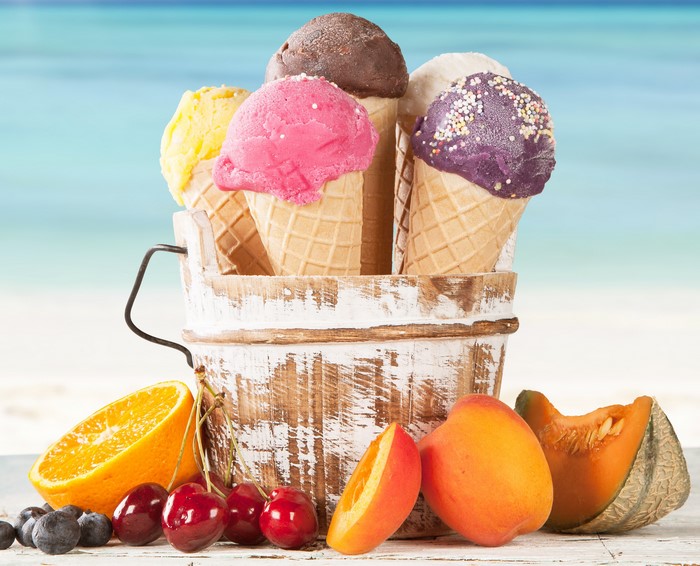 Ice cream cones and fruit on a beach background