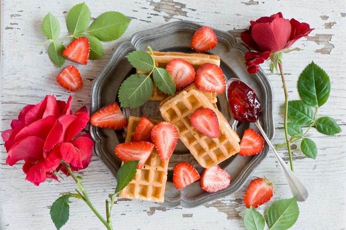 Waffles with strawberries and jam on a plate with roses