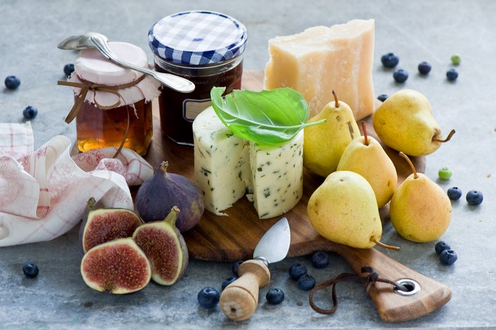 Still-life of cheese, pears, figs, honey, and blueberries