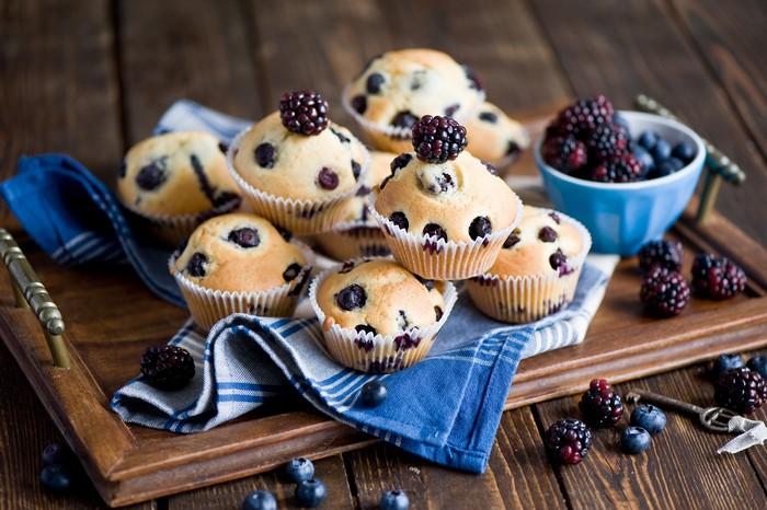 Blueberry muffins with blackberries on a wooden tray