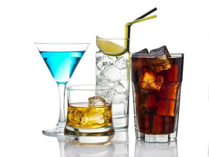 Four alcoholic drinks with ice and garnishes