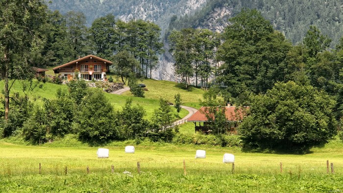 Houses and hay bales in a Swiss mountain landscape