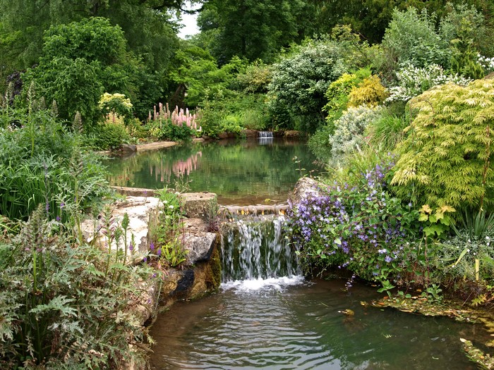 Park waterfall with lush greenery and flowers
