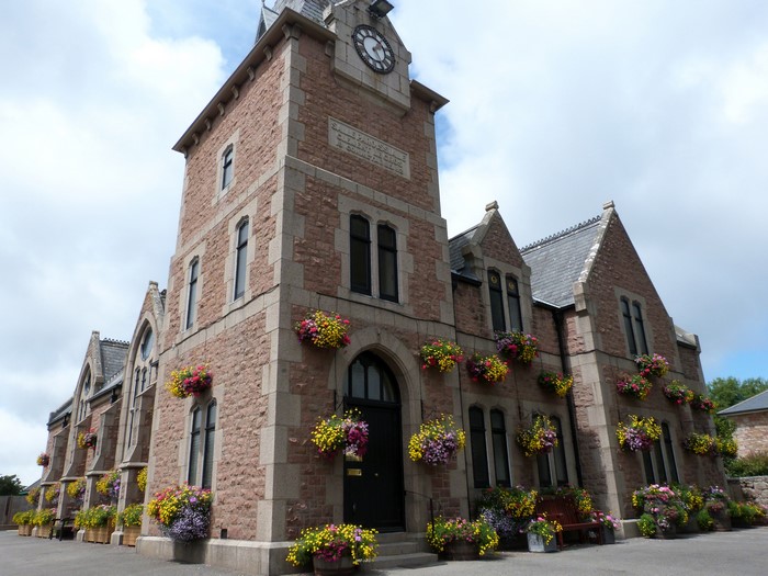 Stone building with clock tower and flower baskets
