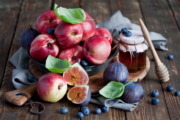 Peaches, figs, blueberries, and honey on a wooden table