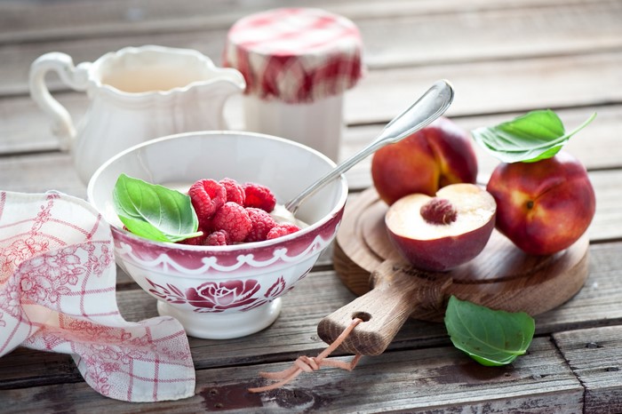 Bowl of raspberries and peaches with cream pitcher