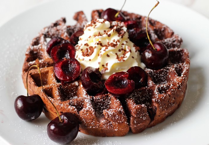 Chocolate waffle with whipped cream and cherries