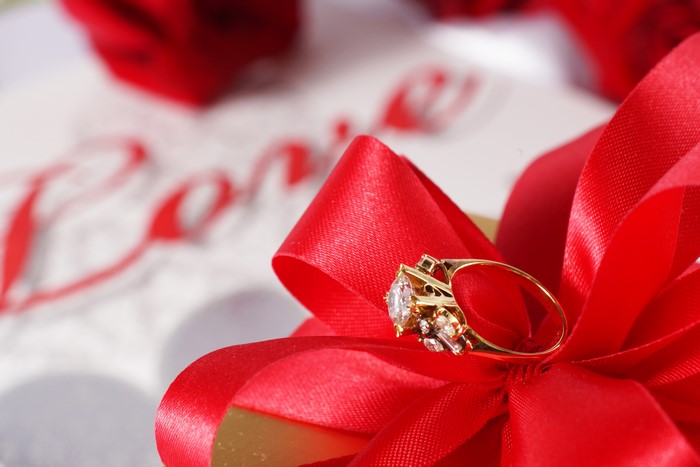 Diamond ring on red bow with 'Love' inscription