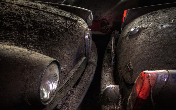 Two dusty vintage cars parked closely together