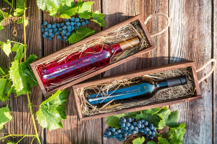 Wine bottles in wooden boxes with grapes and leaves