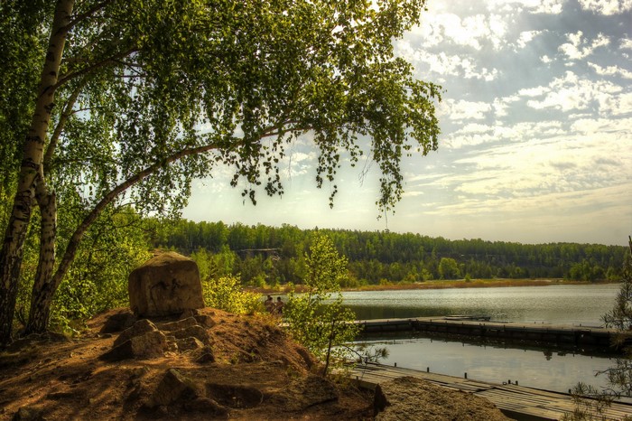 Wooden pier on a lake with trees and clouds