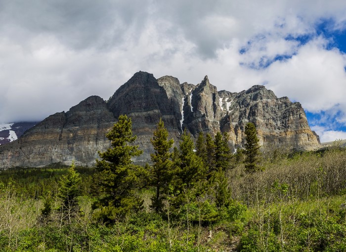 Layered mountains with snow patches and pine trees